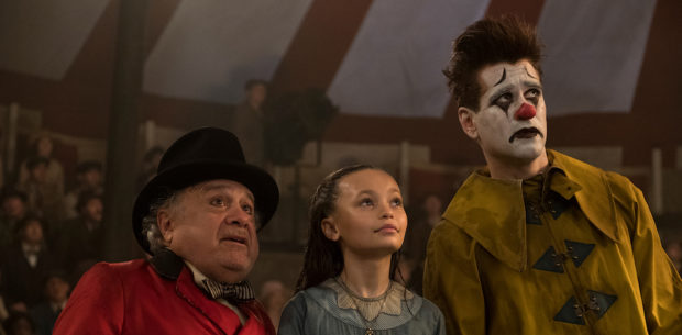 CLOWNING AROUND -- In Tim Burton’s all-new, live-action reimagining of “Dumbo,” circus owner Max Medici (Danny DeVito) calls on former circus star Holt Farrier (Colin Farrell) to care for a newborn elephant whose oversized ears make him a laughingstock in an already struggling circus. Holt ultimately takes his task very seriously—even donning a clown suit to help the flying elephant as he emerges as a star. Daughter Milly (Nico Parker) just might be Dumbo’s biggest fan. “Dumbo” flies into theaters on March 29, 2019. Photo by Jay Maidment. © 2018 Disney Enterprises, Inc. All Rights Reserved.