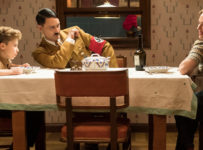 First still from the set of WW2 satire, JOJO RABIT. (From L-R): Jojo (Roman Griffin Davis) has dinner with his imaginary friend Adolf (Writer/Director Taika Waititi), and his mother, Rosie (Scarlet Johansson). Photo by Kimberley French. © 2018 Twentieth Century Fox Film Corporation All Rights Reserved